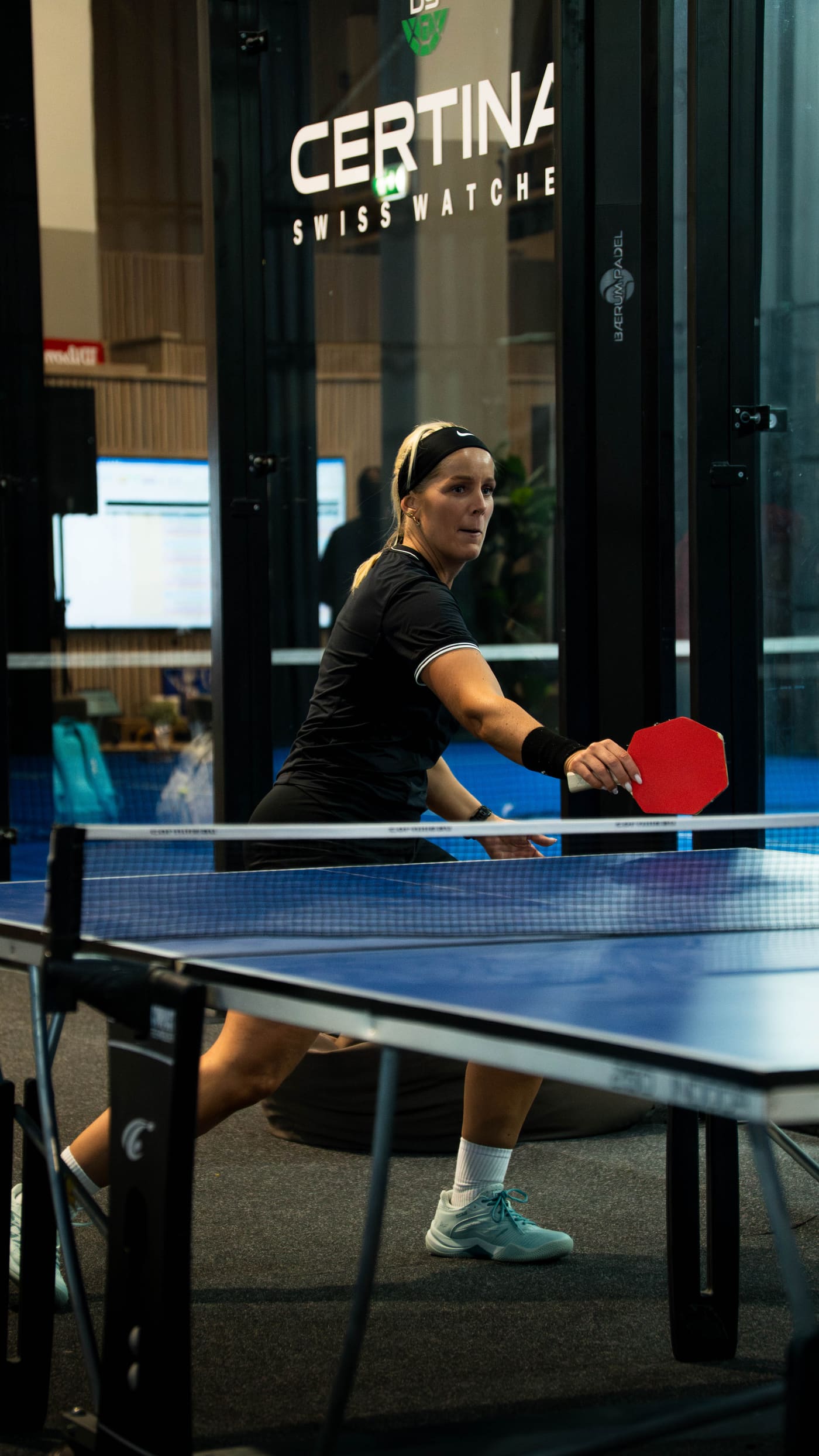 Spiller klar med racket foran Certina-logo hos Bærum Padel